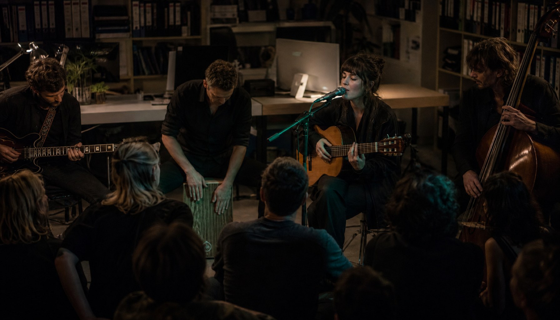Annahstasia und ihre Band spielen konzentriert im engen Bürosetting des NPR Tiny Desk, umgeben von Regalen und Schreibtischen, mit minimaler Technik.