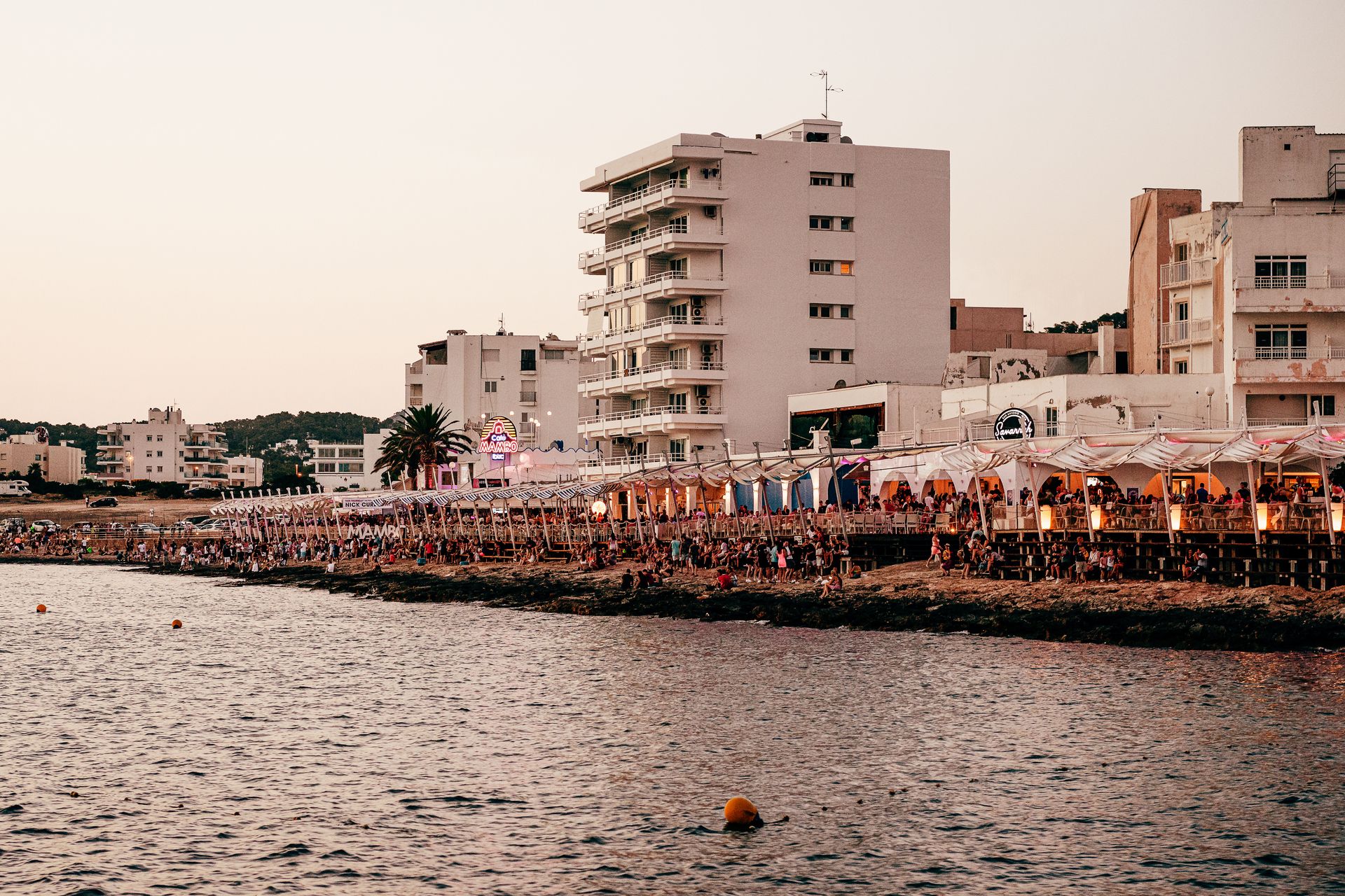 Uferpromenade auf Ibiza bei Sonnenuntergang mit vollen Terrassen